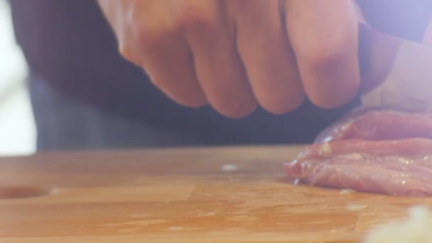 クローズアップマクロ調理の手は キッチンテーブルの上に木製ボード上の薄切りにナイフで専門的に肉をカット — ストック動画