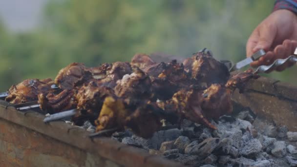 Human hands turning over skewers with kebabs — Stock Video