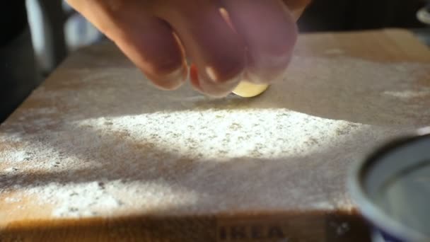 Nahaufnahme Hände legen Teig in Form von Nudelholz auf Bord mit Mehl bedeckt auf Küchentisch bei hellem Licht
