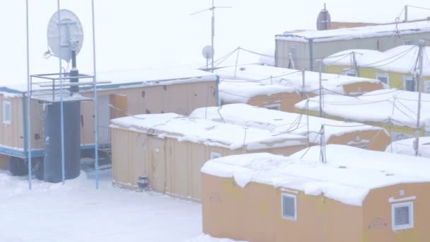 ロシアのヤマルで厚い雪に覆われた建設労働者や時計職人のための小さな黄色プレハブロッジの町 — ストック動画