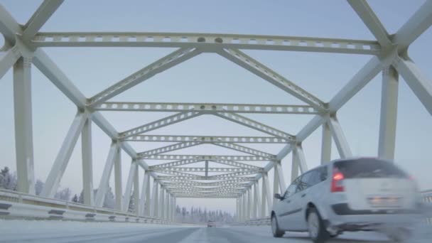 ロシア北部の金属製の梁や柱で作られた素晴らしいアーチの下に新しく建てられた橋の上で白い車が速く動きます — ストック動画