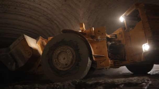 巨大な鉱山機械が石灰岩鉱山の暗い狭いトンネルの中で慎重に動きます — ストック動画