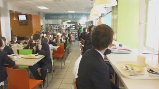 Öğle yemeği ile masalarda oturan öğrenciler — Stok video