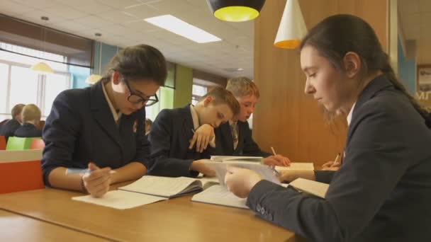 Enfants faisant leurs devoirs à table à la cantine — Video
