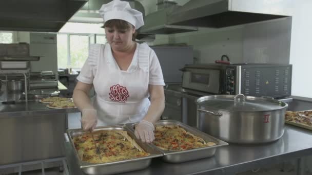 Keuken werknemer snijden heerlijke lasagne — Stockvideo