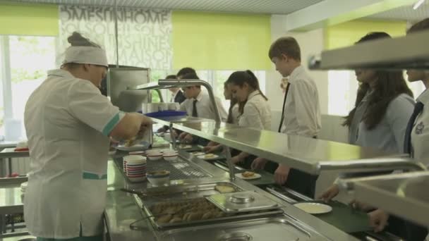 Empregada de bar dando comida para os alunos na cantina — Vídeo de Stock