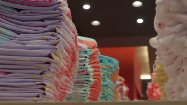 Линии со сложенной стильной одеждой в магазине — стоковое видео