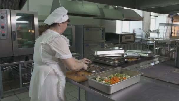 Vrouw snijden groenten bij kantine keuken — Stockvideo