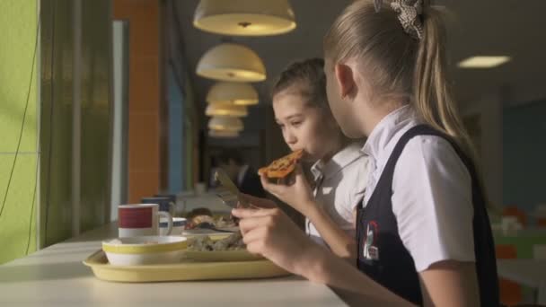 Colegialas en uniforme comiendo en la cantina escolar — Vídeo de stock