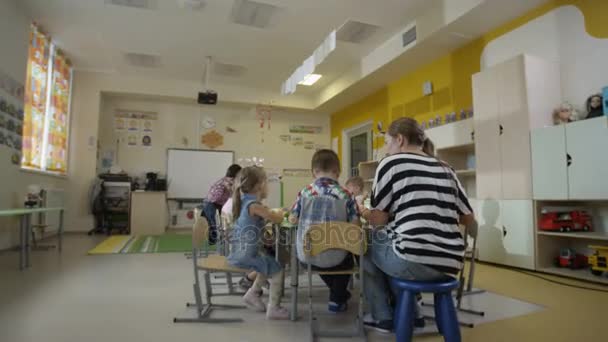 Enfants assis à table à la maternelle — Video