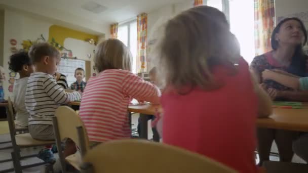 Τα παιδιά που κάθονται στο τραπέζι στο νηπιαγωγείο — Αρχείο Βίντεο