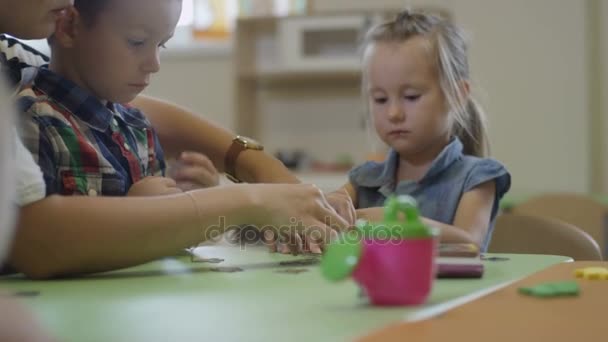 Pépinière-gouvernante aidant garçon dans la salle de jeux — Video