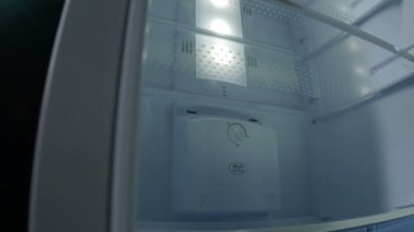 Kamera, cam rafları ve parlak lambası olan, modern beyaz, bitirilmiş buzdolabına doğru hareket ediyor.
