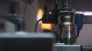 Yakın çekim kamerası otomatik çelik ekipmanların hızlı yeşil kapağı motor yağı ile şişeye çevirdiğini gösteriyor.