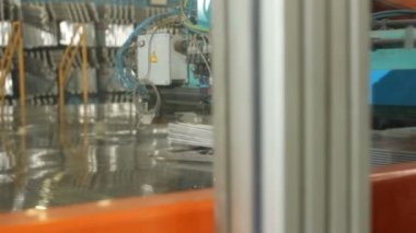 Modern otomatik makine, parlak ışıklandırılmış fabrika atölyesinde çelik plaka üzerinde metal telle çalışır.