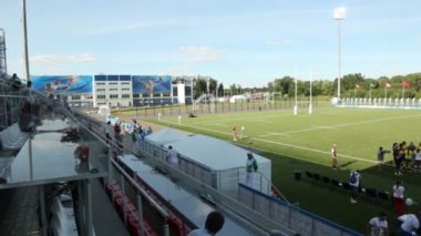 Yeşil stadyumun havadan görünüşlü insanları, gün ışığında mavi gökyüzüne karşı fener verandalarıyla tribünlerde toplanıyor.