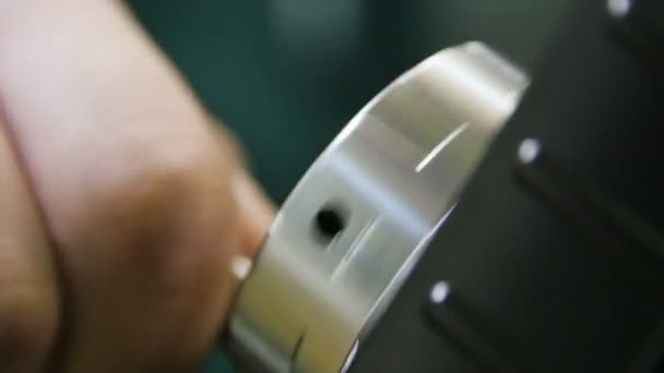 Close-up werknemer draait met de hand glanzend metalen machine deel — Stockvideo
