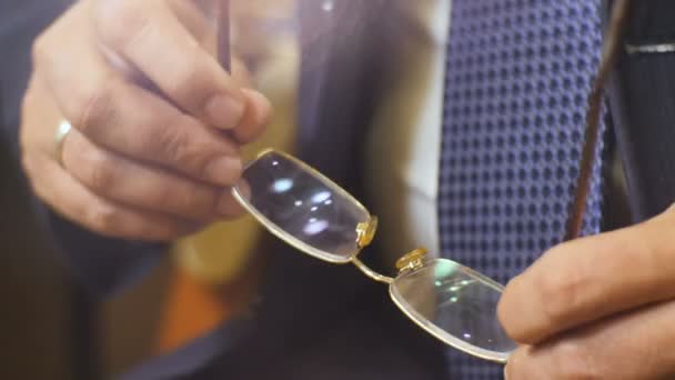 L'homme en costume de bureau tient des lunettes dans les mains et parle — Video