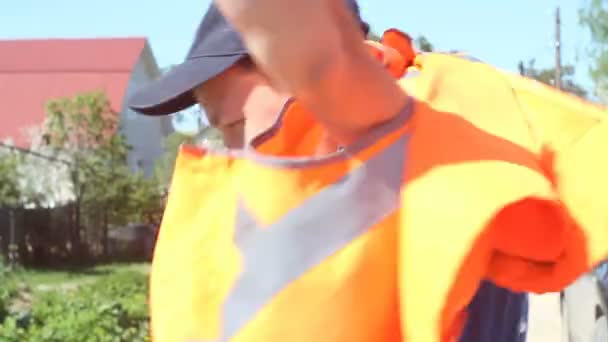Man sätter på orange arbetande vest — Stockvideo