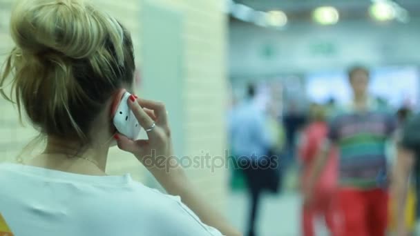 Женщина разговаривает по мобильному телефону в холле — стоковое видео