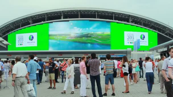 Menschen gehen in der Nähe von Bildschirm an Stadionfassade — Stockvideo