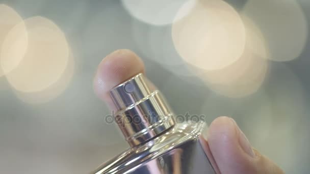 female hand spraying perfume on objective