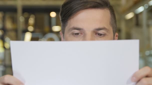 Человек смотрит на бумагу и улыбается — стоковое видео