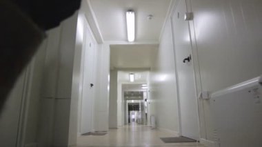 Salehard, Yamal-Nenets / Rusya - 15 Haziran 2012: Alt görüşlü üniformalı işçi 15 Haziran 'da Salehard' da lambalar ve kapılarla aydınlık beyaz duvar boyunca hızla yürüyor