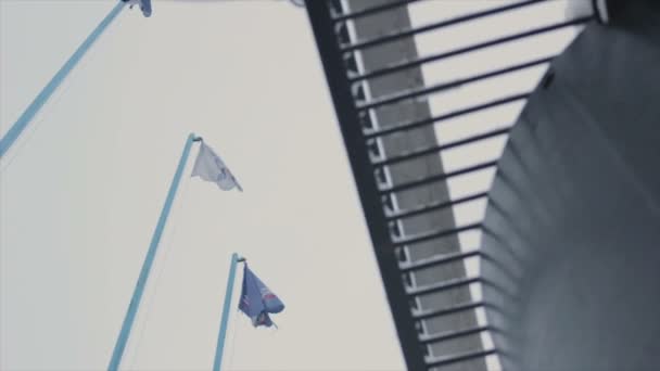 Banderas ondeantes de viento en los asta de bandera — Vídeos de Stock