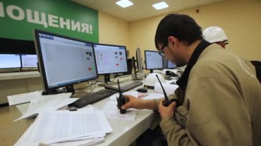 Kazan, Tataristan / Rusya - 09 Mart 2015: Gözlüklü ve üniformalı yan görüş mühendisi ve taşınabilir radyo ile birlikte Kazan 'da 09 Mart' ta bilgisayar başında kağıtlarla çalışıyor