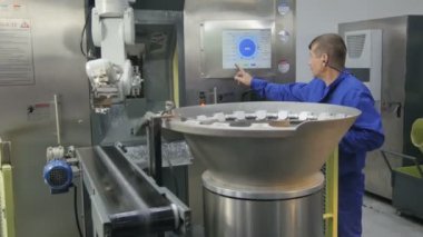 Kazan, Tataristan / Rusya - 11 Mayıs 2016: Mavi üniformalı usta işçi 11 Mayıs 'ta Kazan' da atölyede çalışan robotik kollu modern otomatik makineyi kontrol ediyor
