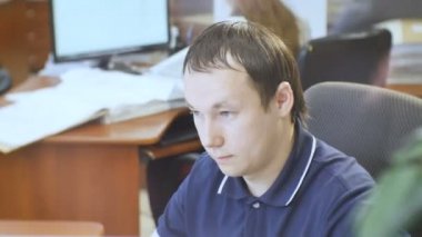 Kazan, Tataristan/Rusya - 12 Haziran 2016: Adam bilgisayarda çalışıyor ve güzel uzun saçlı kız sipariş çizimlerinde ofis masasındaki 12 Haziran kazan koyar