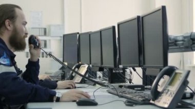 Kazan, Tataristan/Rusya - 20 Aralık 2016: Yan görünümü ciddi erkek üniformalı oturmak ve monitörler bak ve 20 Aralık kazan ön plan üzerinde taşınabilir radyo adam görüşmeler sakallı