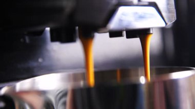 Makro ağır çekim aromatik sıcak espresso dökülen metal Kupası akış arka plan karşı shining