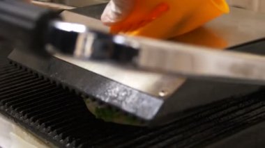 closeup Şef büyük lezzetli hamburger kavurma makinesinde koyar ve sıcak metal kapaklı presler