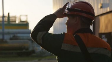 Yavaş çekim arka plan çalışanı fabrika bölgesinde yürüme ve kask ayarlama üretim sürecini kontrol eder