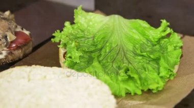 Makro aşçı pembe eldiven taze dilimlenmiş domates salatası lezzetli hamburger hazırlama koyar