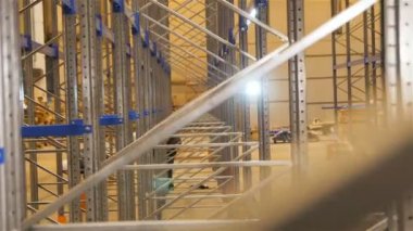büyük modern parlayan metal raflar ve arka planda turuncu yelek işçilerin boyunca kamera taşır