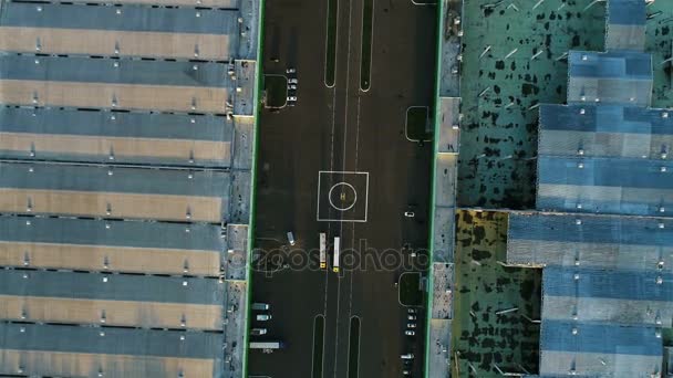 金属屋根の大きな倉庫間の貨物自動車の運転と道路上の着陸場空撮ヘリコプター — ストック動画