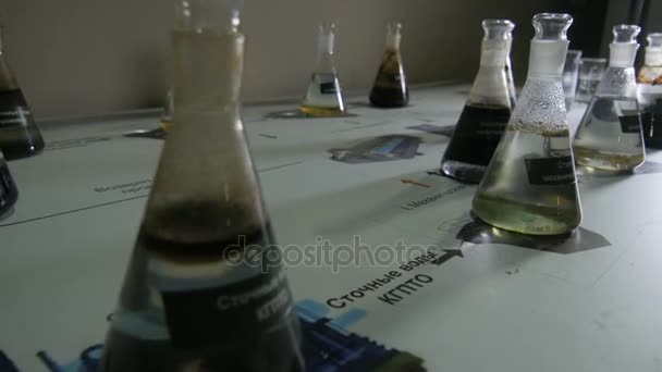 クローズ アップ カメラ方式研究室テーブルと暗いと明確な液体の例と電球に沿って移動します — ストック動画