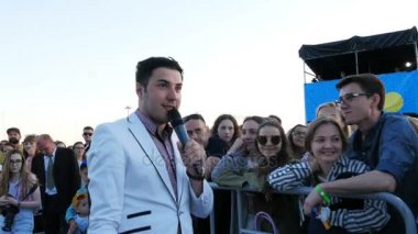 Kazan, Tataristan/Rusya - 03 Kasım 2017: Yakışıklı neşeli şovmen beyaz elbiseli çit Müzik Festivali arkasında mutlu seyirci üzerinde 03 Kasım kazan ile iletişim kurar