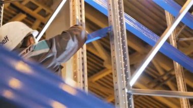 Kazan, Tataristan/Rusya - 25 Ekim 2017: Closeup çalışan beyaz kask içinde mavi çelik bölümü 25 Ekim kazan üzerinde büyük depoda sabitleme depolama Raf monte edilir