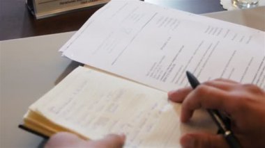 closeup üst görünüm işadamı deri kapaklı defter açılır ve yeni görev Ofis Masası, kalemle yazar