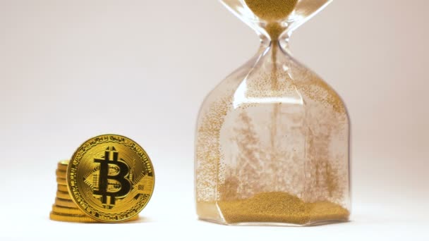 リブにコイン Bitcoin 杭を輝くマクロのそばに注ぐ金明るい背景から砂で砂時計 — ストック動画