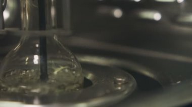 Makro fotoğraf makinesi ile sıvı kaynama ampul gösterir ve farklı laboratuar ekipmanları masanın üstüne taşır