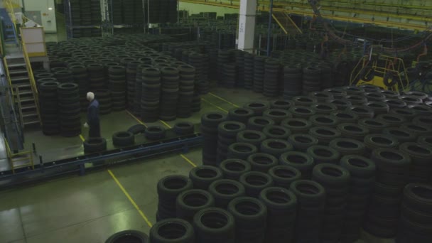 熟練労働者はコンベアからゴム製タイヤを受け取り大完成タイヤ倉庫の床に置く — ストック動画