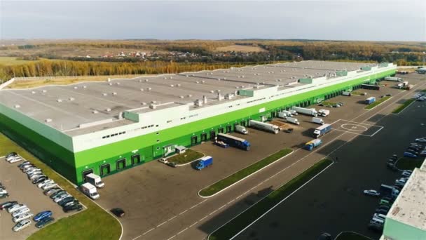 鸟瞰白色和绿色的大型仓库大楼 装载斜坡和巨大的卡车对蓝天 — 图库视频影像