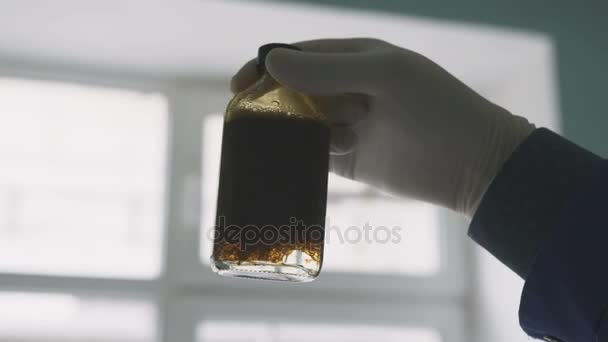 クローズ アップ研究室アシスタント手油ウィンドウに対する水から分離することで小さなガラスのボトルを保持しています — ストック動画