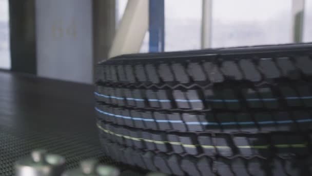 コンベアで運ばれるプロテクターの青と黄色のマークと現代の完成自動車タイヤ — ストック動画