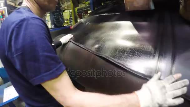 背面视图工人在蓝色 T恤控制黑色轮胎橡胶件连接过程在机器 — 图库视频影像
